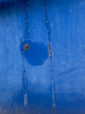 Üzerinde kurşun deliği olan mavi bir duvar.