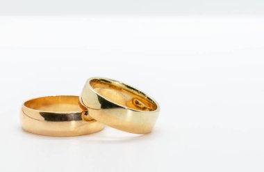 Yakın plan, beyaz arka planda duran iki altın alyans.