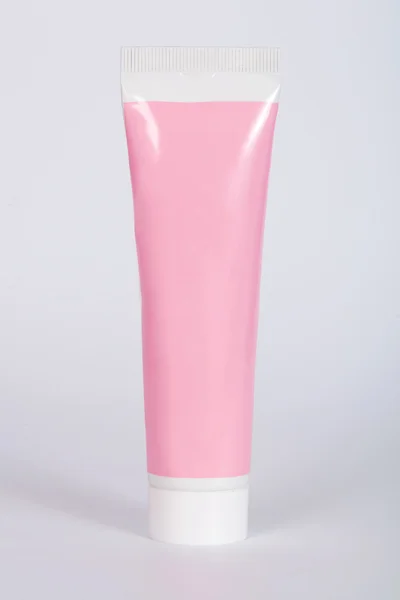 Tubi rosa per crema su sfondo grigio — Foto Stock