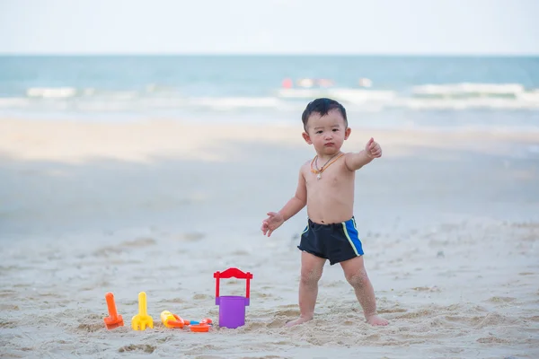 Liten asiatisk pojke 1 år gammal spelar sand på stranden — Stockfoto