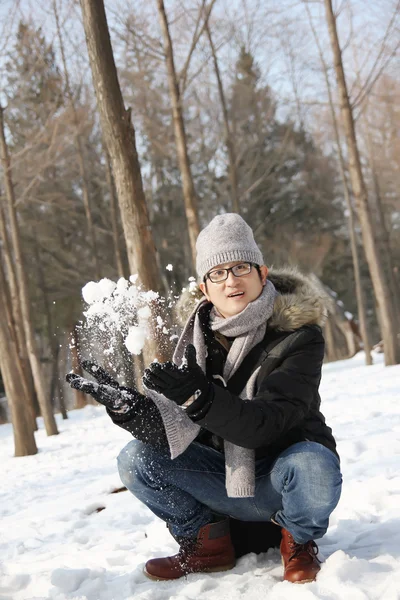 Asiatico bello ragazzo gettare neve in il aria in giardino — Foto Stock
