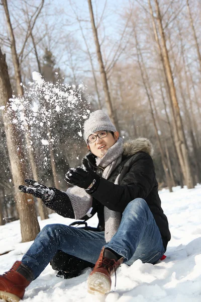 Asiatico bello ragazzo gettare neve in il aria in giardino . — Foto Stock