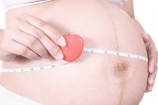 Pregnant woman measuring her stomach with tape measure — Stock Photo, Image