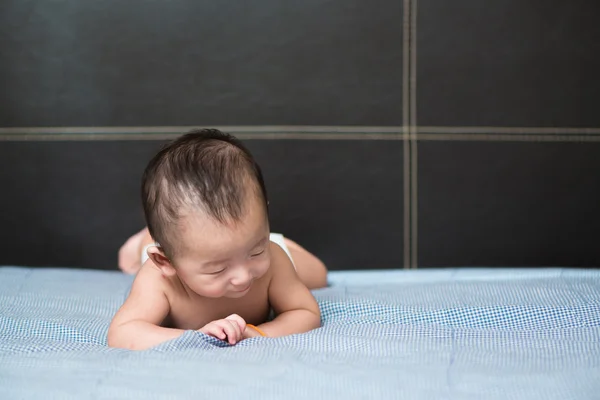 Cute Asian baby lying on a white pillow, on bed — Stock Photo, Image