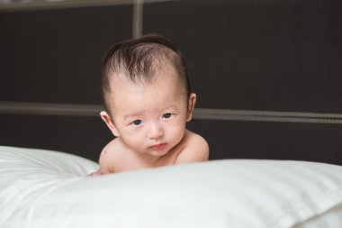 Mutsuz sevimli Asya bebek beyaz bir yastık, yatak yatan