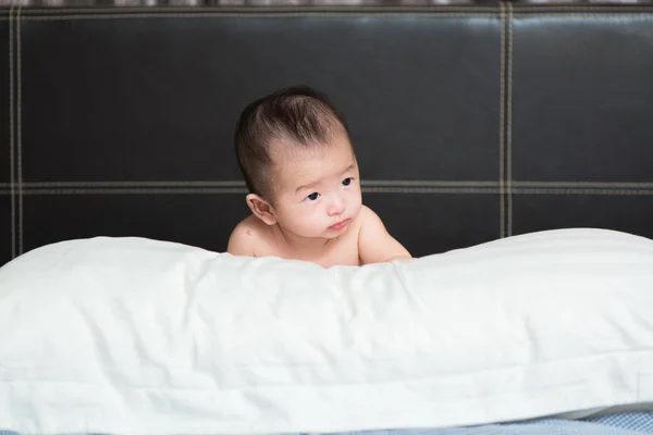 Bonito bebê asiático deitado em um travesseiro branco, na cama — Fotografia de Stock