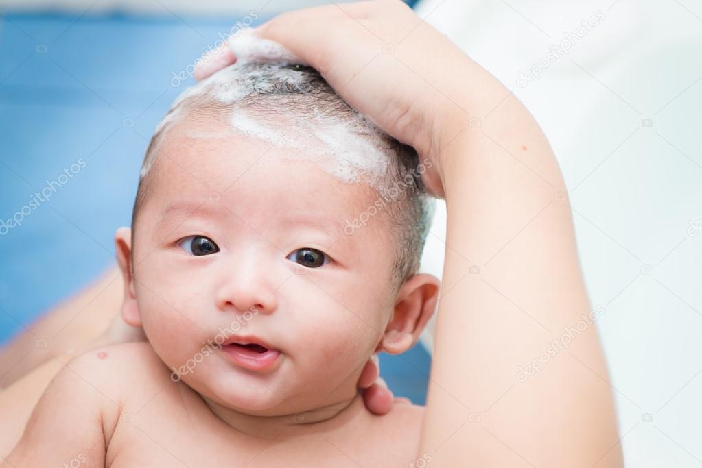 Mother give a bath her newborn baby, infant
