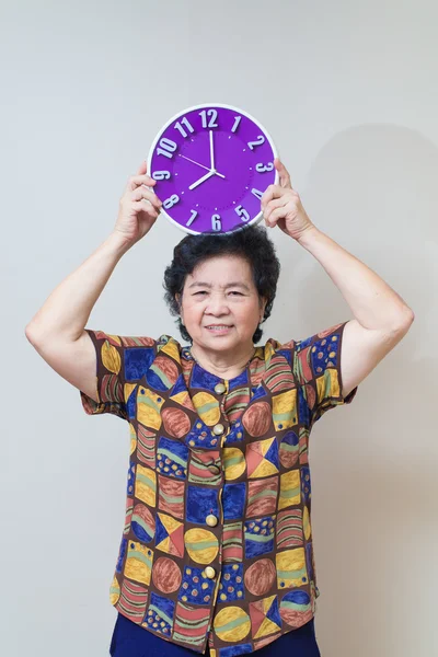 Asian senior woman holding purple clock in studio shot, specialt — Stock Photo, Image