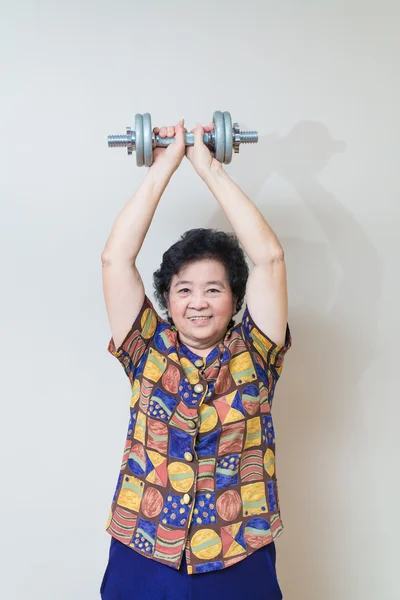 Strong Asian senior woman lifting weights, in studio shot, speci — Stock Photo, Image