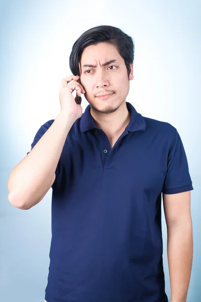 Asian guy with mobile phone in hand on blue background — Stock Photo, Image