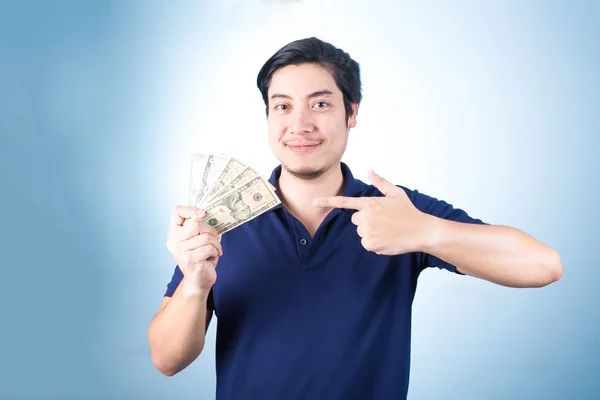 Азиатский красавчик держит деньги, стоя на синем бэкгро. — стоковое фото