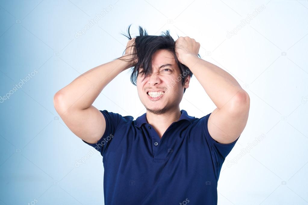 Asian handsome man holding his head frowning with worry. pulling