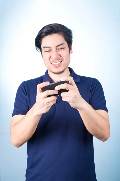 Chico asiático con teléfono móvil en la mano, sobre fondo azul — Foto de Stock