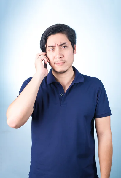 Asian guy with mobile phone in hand, on blue background — Stock Photo, Image