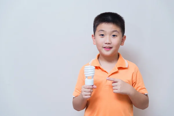 Asian boy holding a lamp, energy saving lamp, — Stock Photo, Image