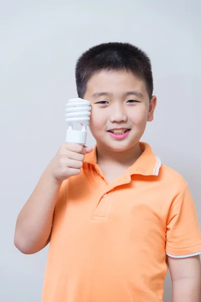 Asiatiska boy håller en lampa, energisparande lampa, — Stockfoto