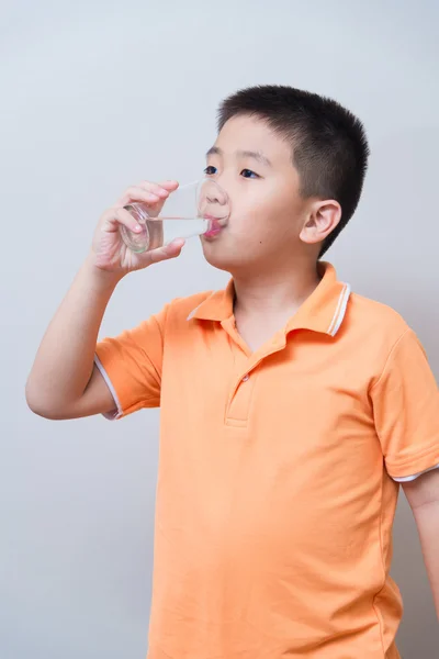 Asiatischer Junge trinkt Wasser aus Glas — Stockfoto