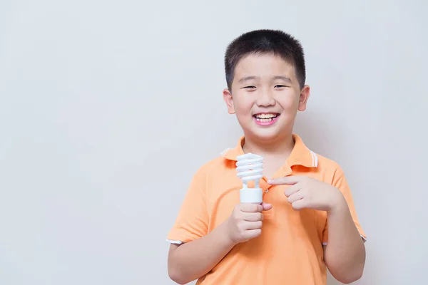 Asiatischer Junge hält eine Lampe, Energiesparlampe, — Stockfoto