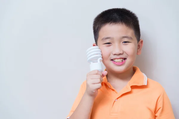 Niño asiático sosteniendo una lámpara, lámpara de ahorro de energía , — Foto de Stock