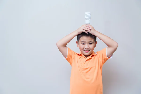 Niño asiático sosteniendo una lámpara, lámpara de ahorro de energía , — Foto de Stock