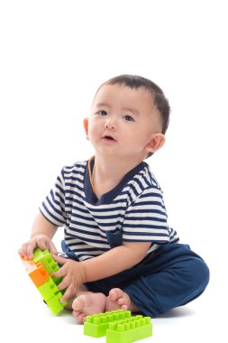 Asya bebek üzerinde beyaz plastik inşaat oyuncaklar ile oynama 