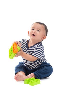 Asya bebek üzerinde beyaz plastik inşaat oyuncaklar ile oynama 