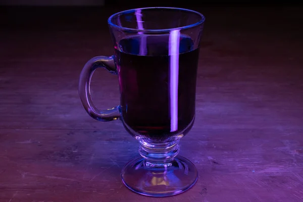 Cappuccino Glas Mit Dunkler Flüssigkeit Und Neonlicht Auf Einem Holztisch — Stockfoto