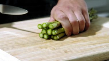 Şef kuşkonmazı yavaş çekimde keser, şef salata yapar, kuşkonmazı yakın plan doğrar.