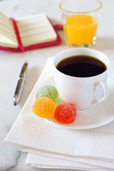 Morning coffee, orange juice, jelly sweets and notebook — Stock Photo, Image