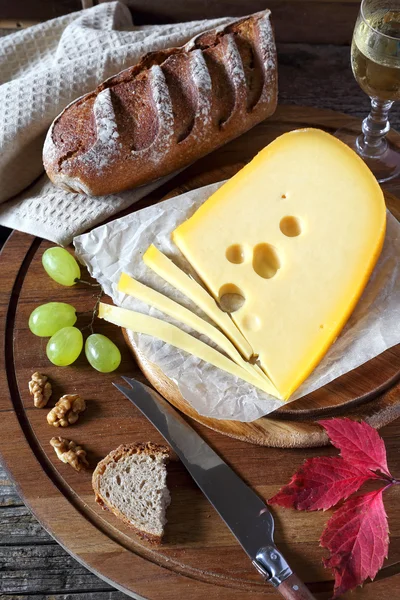 Maasdam sýr, chléb, hrozny a sklenice na víno — Stock fotografie