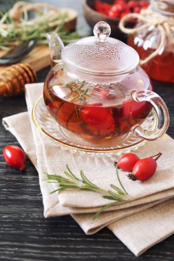 Sağlıklı sıcak kış içeceği. Çaydanlıkta gül kalçası çayı, biberiye ve koyu arkaplanda böğürtlen.