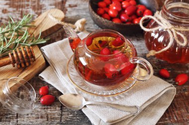 Sağlıklı sıcak kış içeceği. Çaydanlıkta gül kalçası çayı, biberiye ve ahşap arka planda böğürtlen.