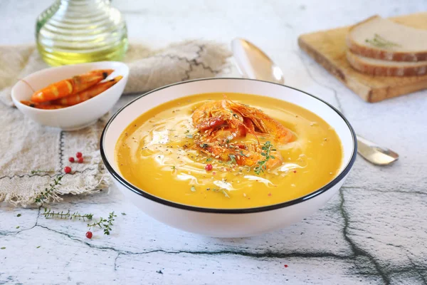 Pumpkin cream soup with fried shrimps, bread and olive oil on light background — Stock Image Pumpkin Cream Soup Fried Shrimps Bread Olive Oil Light Background Royalty Free Stock Photos