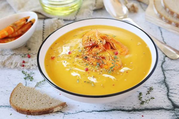Pumpkin cream soup with fried shrimps, bread and olive oil on light background — Stock Image Pumpkin Cream Soup Fried Shrimps Bread Olive Oil Light Background Stock Image