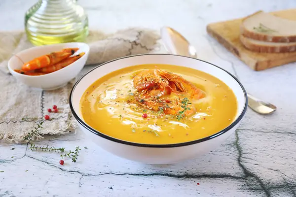 Pumpkin cream soup with fried shrimps, bread and olive oil on light background — Stock Image Pumpkin Cream Soup Fried Shrimps Bread Olive Oil Light Background Stock Image