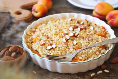 Yaz tatlısı. Taze kayısı parçacıkları, ahşap zemin üzerinde seramik tabakla süslenmiş bademler.