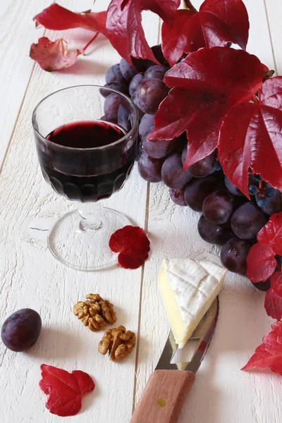 Куча красного винограда, бокал и осенний лист — стоковое фото