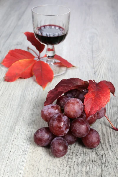 Куча красного винограда, бокал и осенний лист — стоковое фото