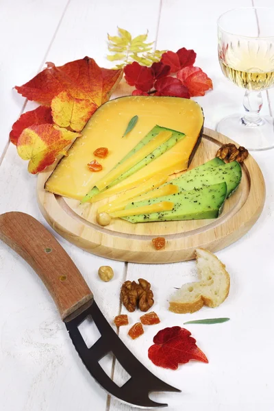 Cheese platter, solid cheese, autumn leaves and wineglass — Stock Photo, Image