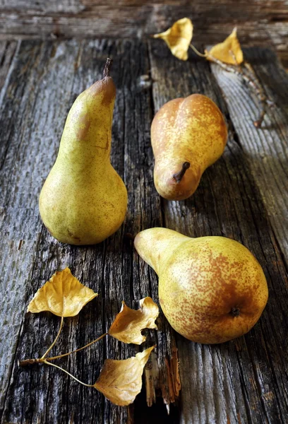 Three yellow pears and autumn leaves — Stock Photo, Image