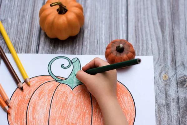 child paints a pumpkin