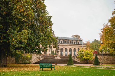 Sonbahar yaprağı ve Almanya 'nın Fulda şehrinde yeşil bir park bankı olan lüks bir otel.