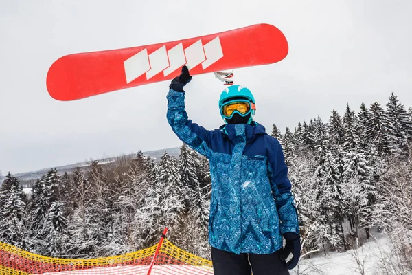 Persona con una tabla de snowboard en la estación de esquí —  Fotos de Stock