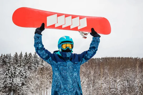 Persona con una tabla de snowboard en la estación de esquí —  Fotos de Stock