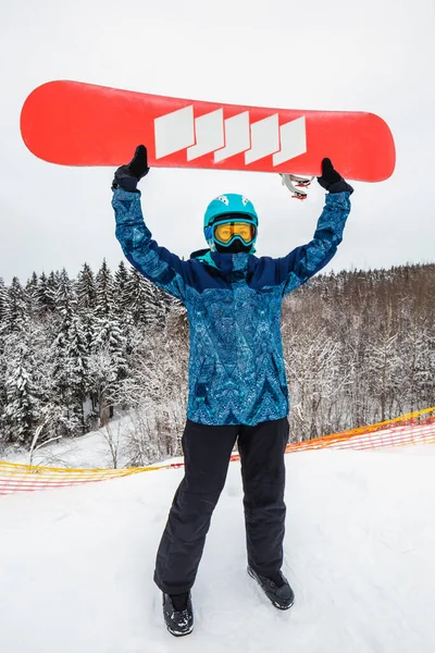 Persona con una tabla de snowboard en la estación de esquí —  Fotos de Stock