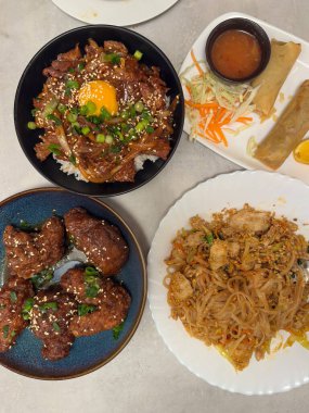 Çeşitli Asya mutfağından canlı yayılmış yumurta sarısı ile lezzetli bir Japon Gyudon sığır eti kasesi, soslu çıtır börek, jöleli tavuk parçaları ve sağlıklı bir porsiyon