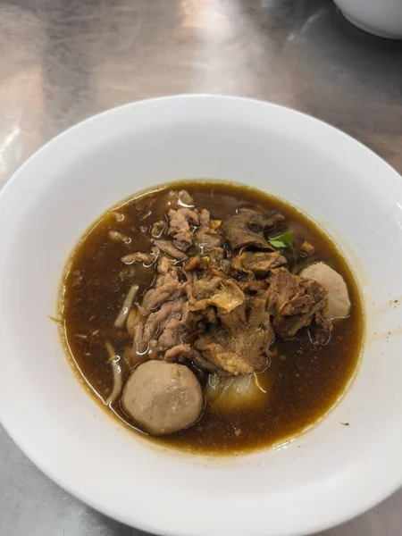 Otantik Tayland et teknesi Kuay Teow Reua 'yı beyaz bir kasede eritiyor. Yumuşak dilimlenmiş sığır eti, lezzetli köfteler, ve zengin, aromatik koyu bir et suyu sağlıklı ve lezzetli bir yemek yaratır, geleneksel Tayland yemeği sergilenir.