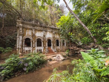 Chiang Mai, Tayland 'daki Antik Wat Pha Lat tapınağı, yemyeşil bir tropikal ormanın içinde. Yüzyıllar süren ruhani huzuru yansıtan, sakin bir akıntıya karşı yıpranmış dış görünüşü..