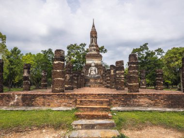 Tayland 'daki Sukhothai Tarih Parkı' ndaki Wat Mahathat 'ın harabelerini araştırın. Antik tuğla temeller, yıpranmış sütunlar ve sakin bir Buda heykeli tarihsel ihtişamın kanıtı.