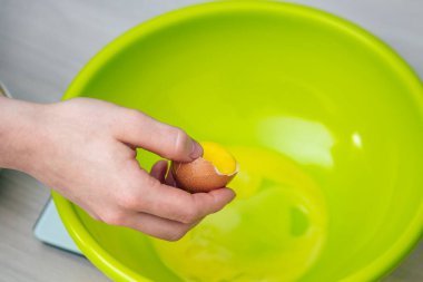 Yakın plan kadının elleri yumurtayı kırıyor ve sarısını beyazdan ayırıyor..